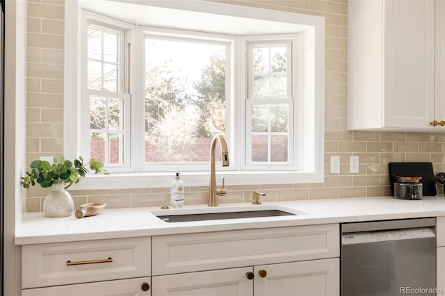 kitchen with backsplash, sink, white cabinets, and stainless steel dishwasher