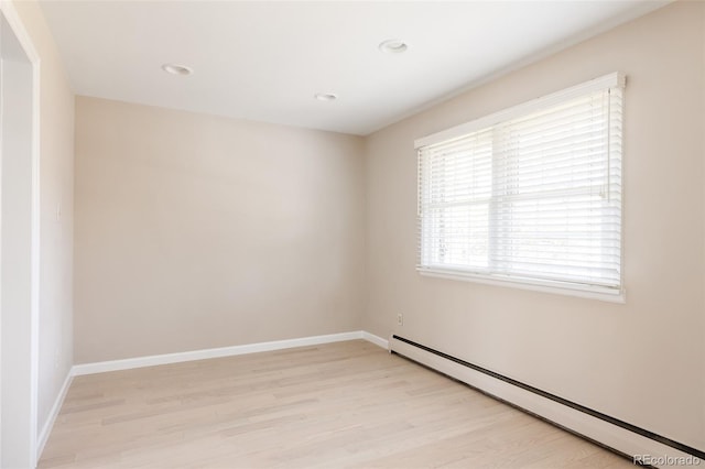 unfurnished room with baseboard heating and light hardwood / wood-style flooring