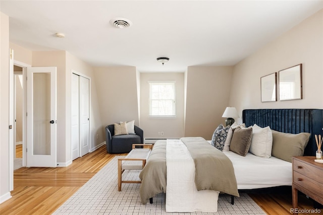 bedroom featuring baseboard heating, a closet, and light hardwood / wood-style flooring