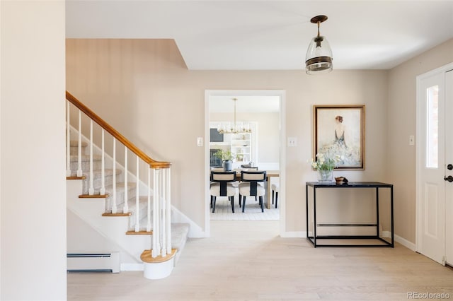 entrance foyer featuring a chandelier, light wood-type flooring, and a baseboard heating unit