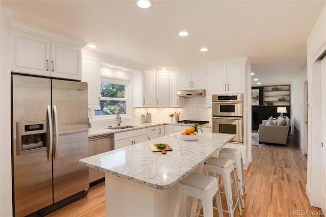 kitchen with white cabinetry, sink, stainless steel appliances, and light hardwood / wood-style flooring