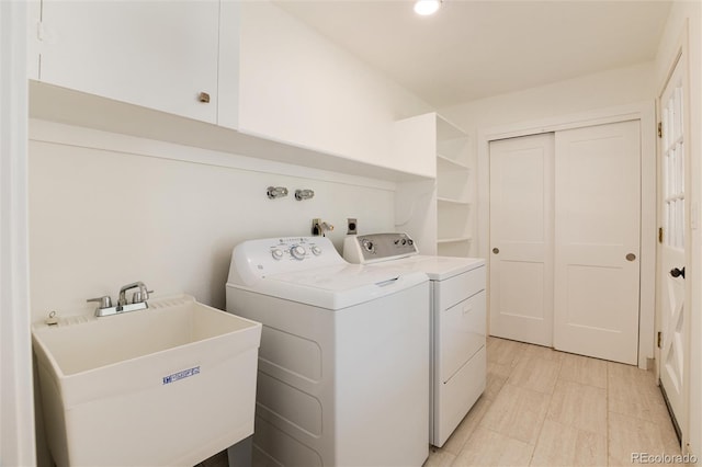 washroom with cabinets, separate washer and dryer, and sink