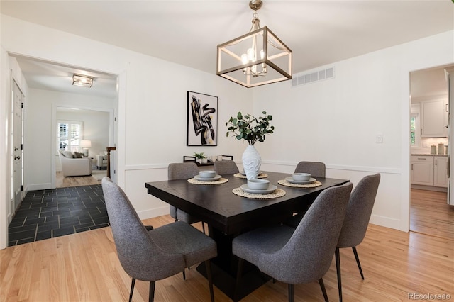 dining space with hardwood / wood-style floors and an inviting chandelier