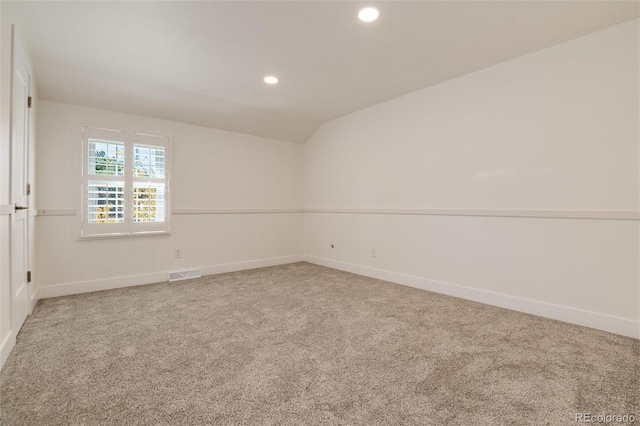 carpeted spare room with vaulted ceiling