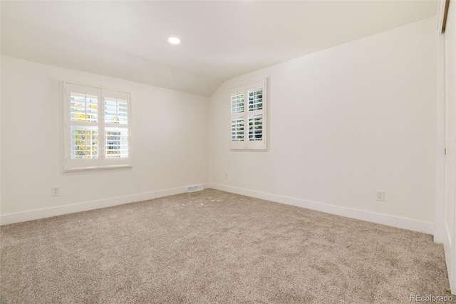 carpeted spare room with lofted ceiling