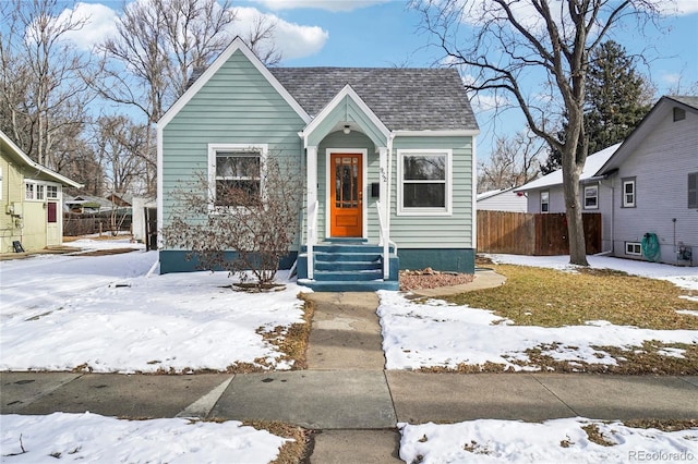 bungalow featuring a shingled roof and fence