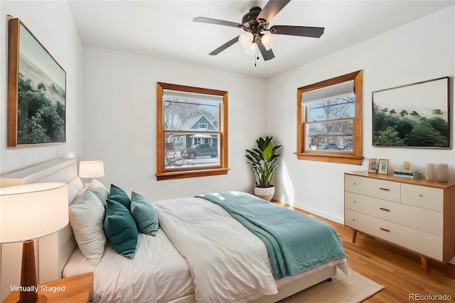 bedroom with baseboards, ceiling fan, and light wood-style floors