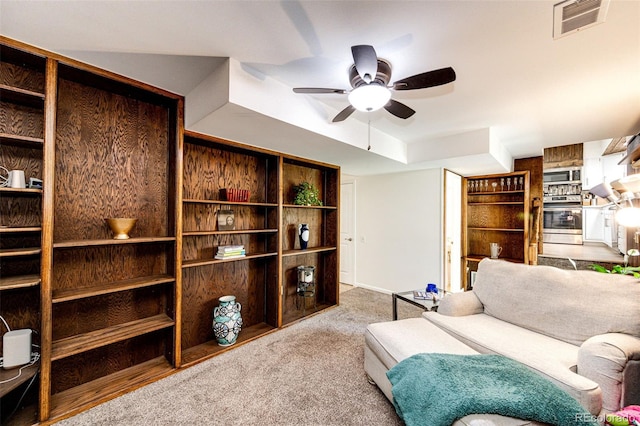 living area featuring light carpet and ceiling fan