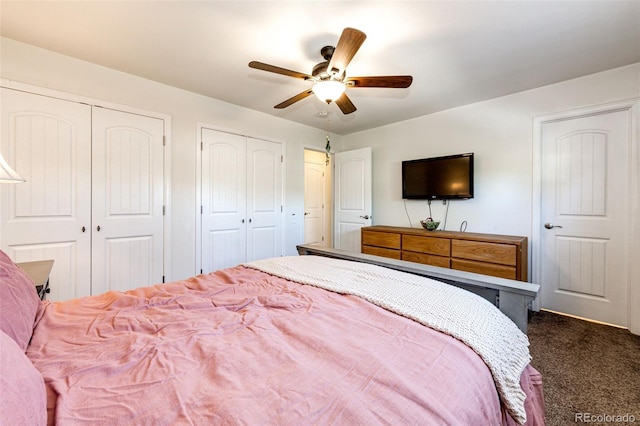 bedroom featuring ceiling fan, dark carpet, and multiple closets