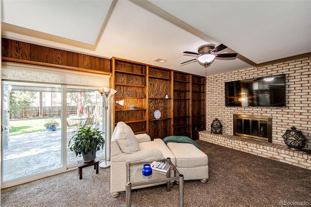 carpeted living room with ceiling fan, a fireplace, and built in features