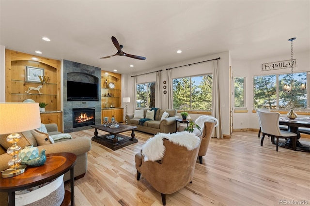 living room featuring built in features, recessed lighting, a fireplace, and light wood finished floors