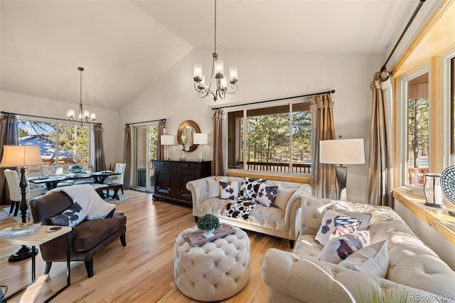 living room featuring high vaulted ceiling, light wood-style flooring, and an inviting chandelier