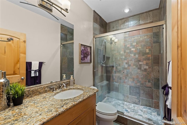 full bathroom with a stall shower, vanity, and toilet