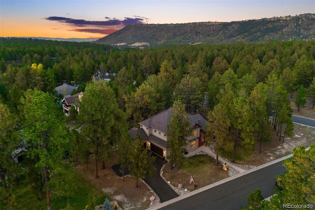 aerial view at dusk featuring a forest view and a mountain view