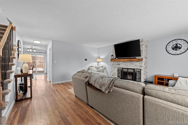 living room featuring a stone fireplace, hardwood / wood-style floors, and a textured ceiling