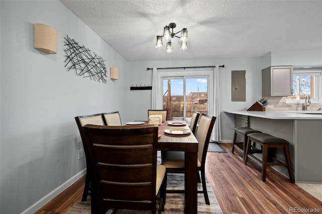 dining area featuring electric panel, dark wood-type flooring, a healthy amount of sunlight, and a textured ceiling