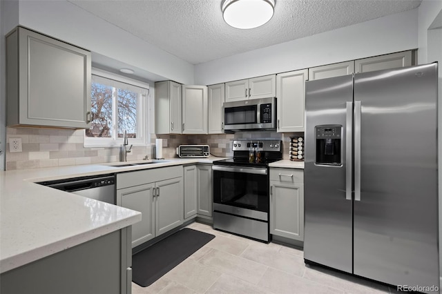 kitchen with backsplash, gray cabinetry, sink, and appliances with stainless steel finishes