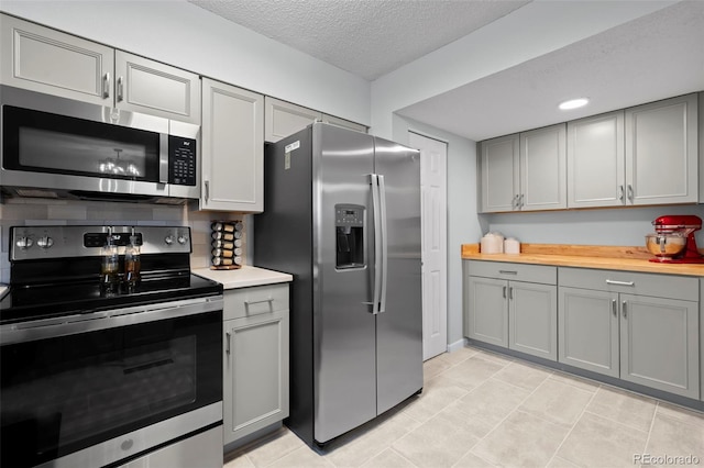 kitchen featuring gray cabinetry, light tile patterned floors, stainless steel appliances, and a textured ceiling