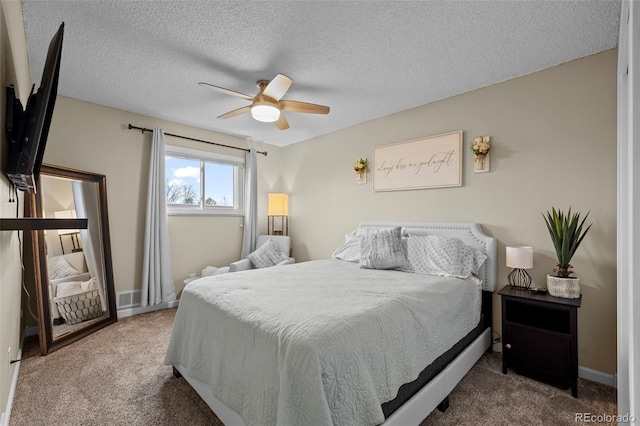 carpeted bedroom featuring ceiling fan and a textured ceiling