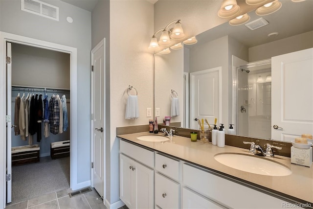 bathroom featuring a shower with door, vanity, and tile patterned flooring