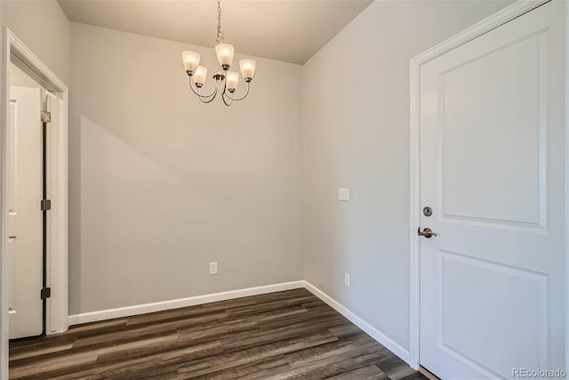 unfurnished room featuring dark wood-type flooring and a chandelier