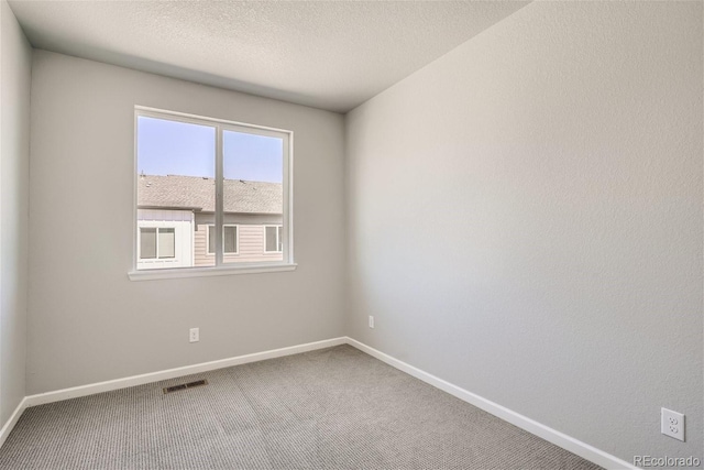 carpeted empty room with a textured ceiling