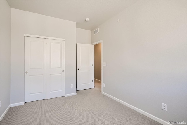 unfurnished bedroom featuring light carpet and a closet