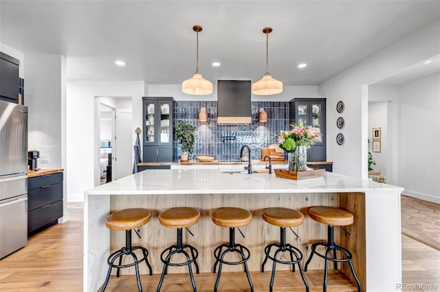 202 October Pl, Castle Rock, CO 80104 - kitchen with wall chimney exhaust hood, freestanding refrigerator, a sink, light stone countertops, and a breakfast bar area