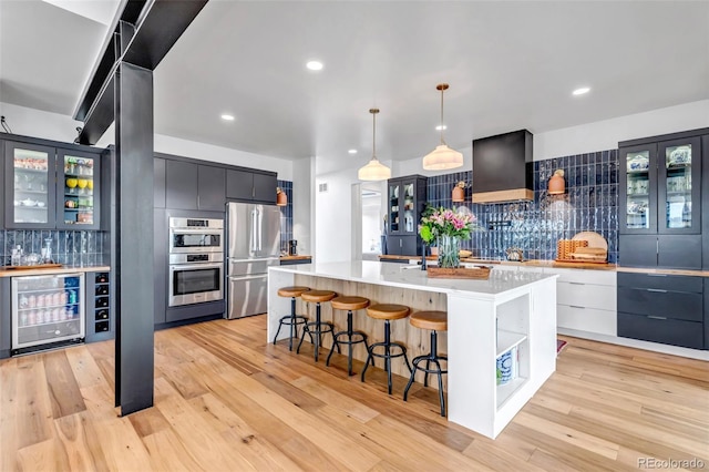 202 October Pl, Castle Rock, CO 80104 - kitchen with beverage cooler, stainless steel appliances, custom exhaust hood, backsplash, and light countertops