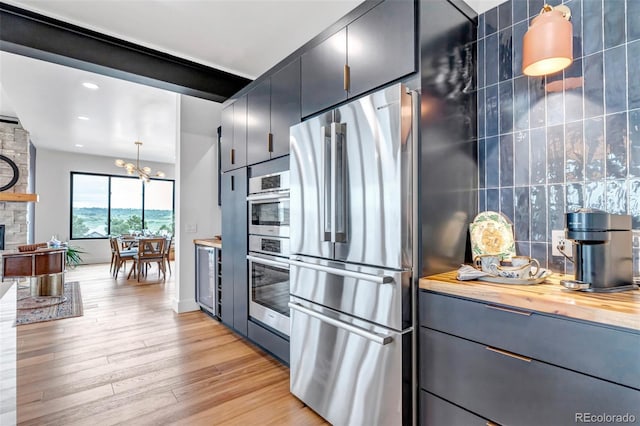 202 October Pl, Castle Rock, CO 80104 - kitchen featuring stainless steel fridge, light wood-type flooring, butcher block counters, a fireplace, and pendant lighting