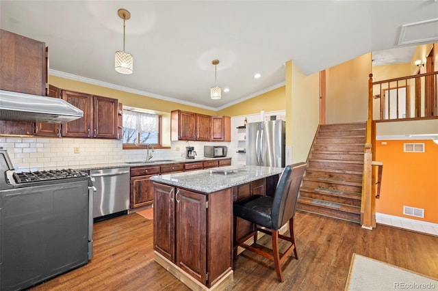 kitchen featuring sink, appliances with stainless steel finishes, dark hardwood / wood-style flooring, a kitchen island, and pendant lighting