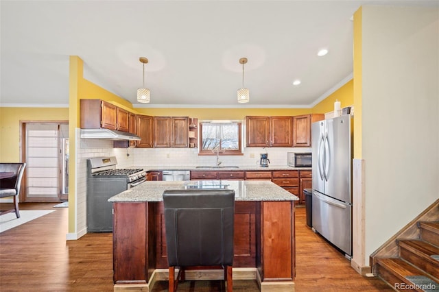 kitchen with pendant lighting, stainless steel appliances, a center island, and light stone countertops