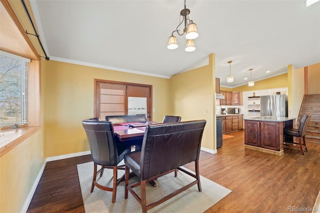 dining space featuring lofted ceiling, dark hardwood / wood-style flooring, ornamental molding, and an inviting chandelier