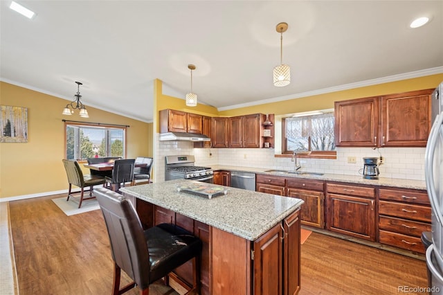 kitchen with pendant lighting, sink, stainless steel appliances, and light stone countertops