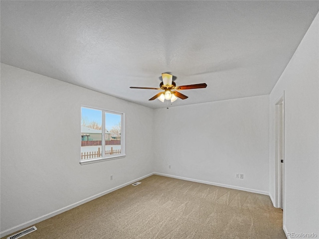 empty room with ceiling fan, light carpet, and a textured ceiling