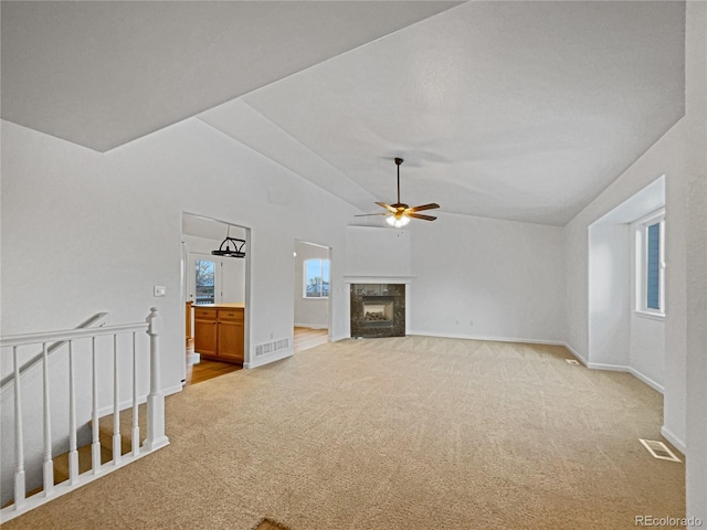 unfurnished living room with lofted ceiling, ceiling fan, a fireplace, and light carpet