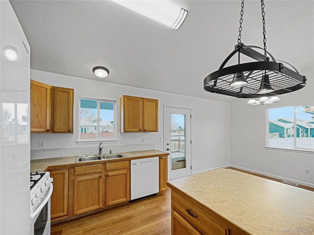 kitchen with sink, white appliances, plenty of natural light, and decorative light fixtures