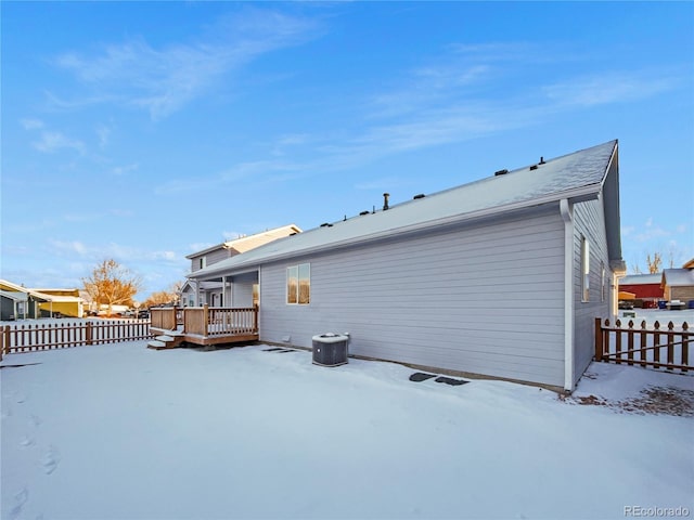 snow covered rear of property featuring a wooden deck and central AC unit