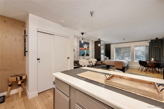 kitchen with decorative light fixtures, a textured ceiling, and light hardwood / wood-style floors