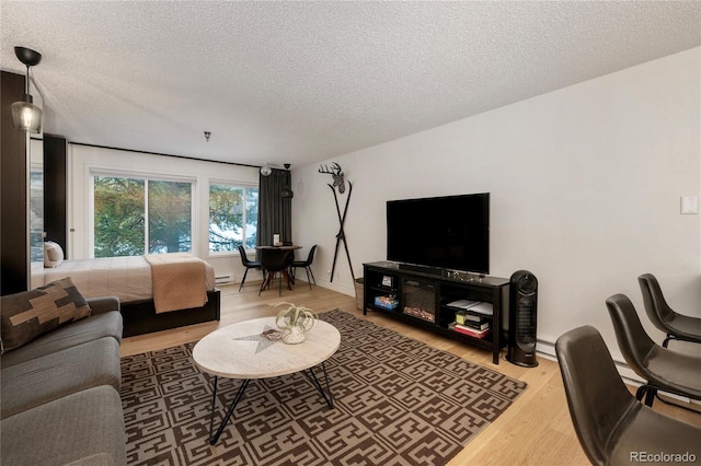 living room with baseboard heating, hardwood / wood-style floors, and a textured ceiling