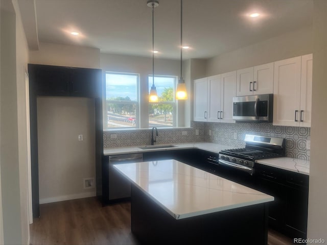 kitchen with hanging light fixtures, sink, backsplash, appliances with stainless steel finishes, and a center island