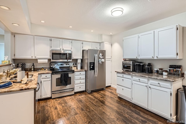 7198 Eaton Ct, Arvada, CO 80003 - kitchen with appliances with stainless steel finishes, dark wood-type flooring, white cabinetry, recessed lighting, and a textured ceiling