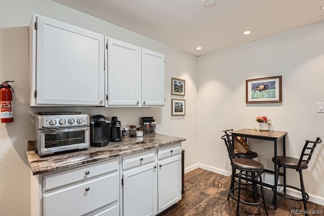 7198 Eaton Ct, Arvada, CO 80003 - kitchen featuring dark wood-type flooring, white cabinets, stone countertops, baseboards, and recessed lighting