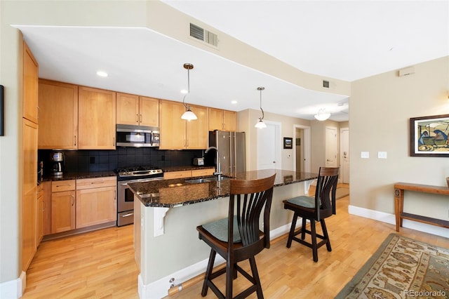 1560 Milwaukee St Unit 240, Denver, CO 80206 - kitchen featuring stainless steel appliances, a sink, light wood finished floors, a kitchen breakfast bar, and tasteful backsplash