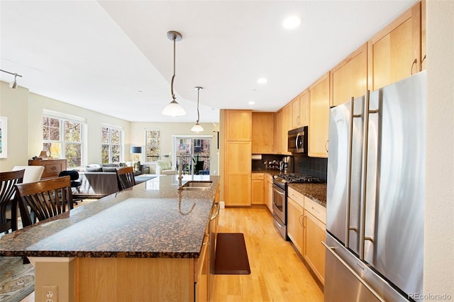 1560 Milwaukee St Unit 240, Denver, CO 80206 - kitchen featuring appliances with stainless steel finishes, a sink, light brown cabinets, light wood-type flooring, and an island with sink