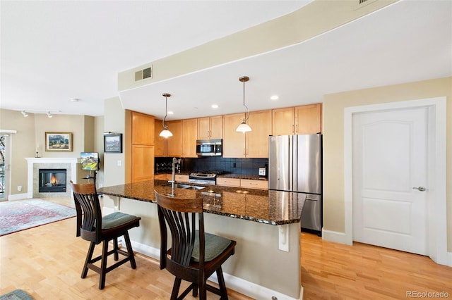 1560 Milwaukee St Unit 240, Denver, CO 80206 - kitchen with stainless steel appliances, light wood-style flooring, decorative backsplash, a sink, and a kitchen bar