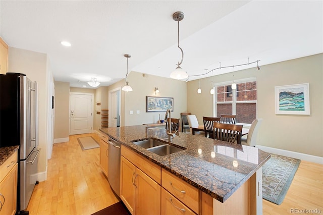 1560 Milwaukee St Unit 240, Denver, CO 80206 - kitchen featuring stainless steel appliances, a sink, light wood finished floors, an island with sink, and baseboards