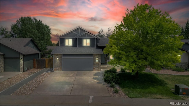 view of front of property featuring a garage, stone siding, roof with shingles, and driveway