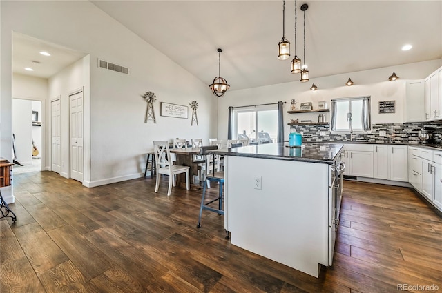 40051 Cold Iron Rd, Ramah, CO 80832 - kitchen with dark countertops, dark wood-style flooring, a center island, tasteful backsplash, and white cabinets