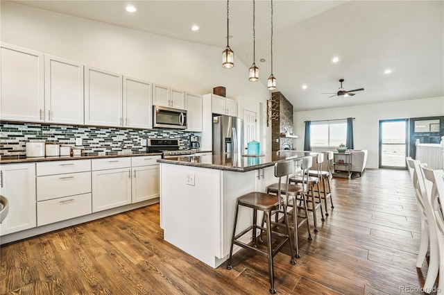 40051 Cold Iron Rd, Ramah, CO 80832 - kitchen featuring appliances with stainless steel finishes, a kitchen breakfast bar, a center island, high vaulted ceiling, and backsplash